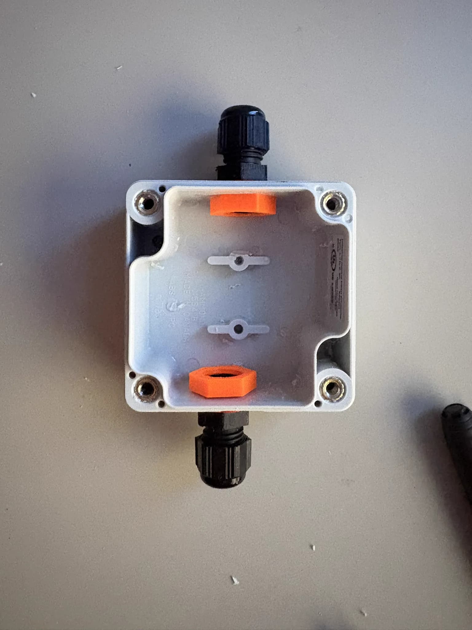 Closed electrical box with cable glands and orange mounting tabs